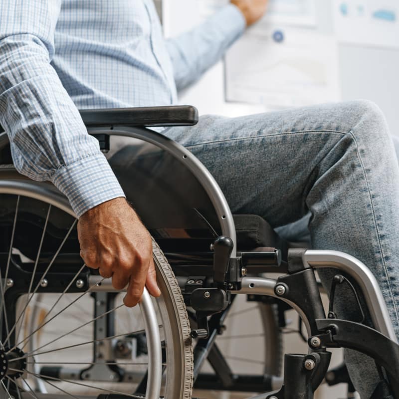 person sitting in wheelchair with hand on wheel