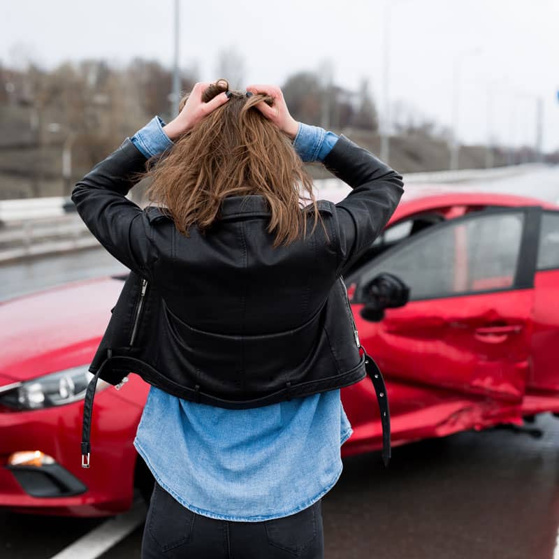 Person clutching hair while looking at car after accident
